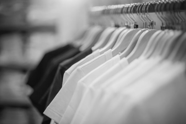 T-shirts on hangers. Shopping in store. Clothes on hangers in shop for sale. Blur background. Fashionable clothes in a boutique. Various clothing on market.